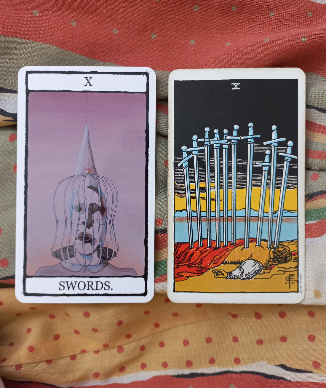 Image of 2 tarot cards featuring the 10 of Swords. One card shows a sullen face in a cage and the other shows a figure lying on the ground with a dark background.