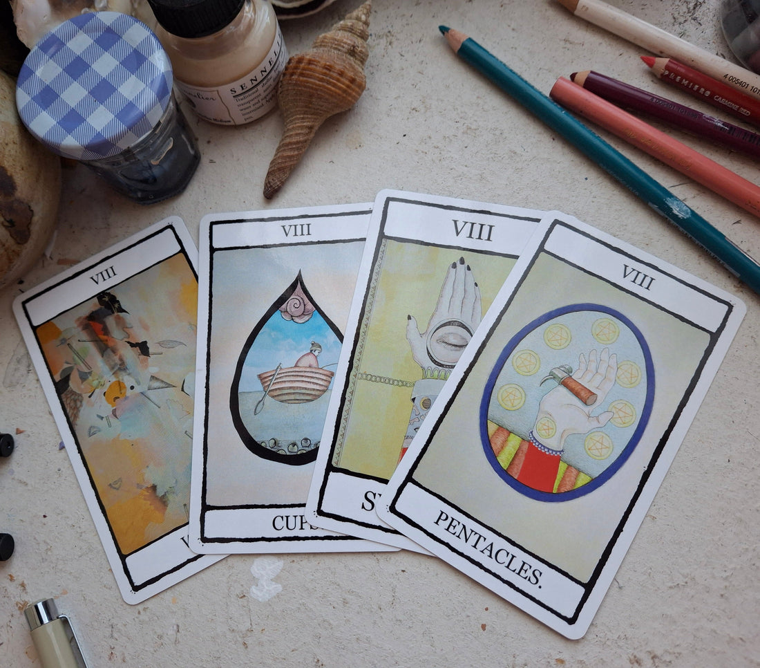 Four colourfully illustrated minor arcana eights from The Falling Card Tarot, arranged on a table surrounded by art materials.