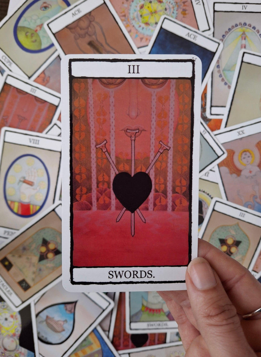 3 of Swords tarot card featuring hand illustrated black heart with red background