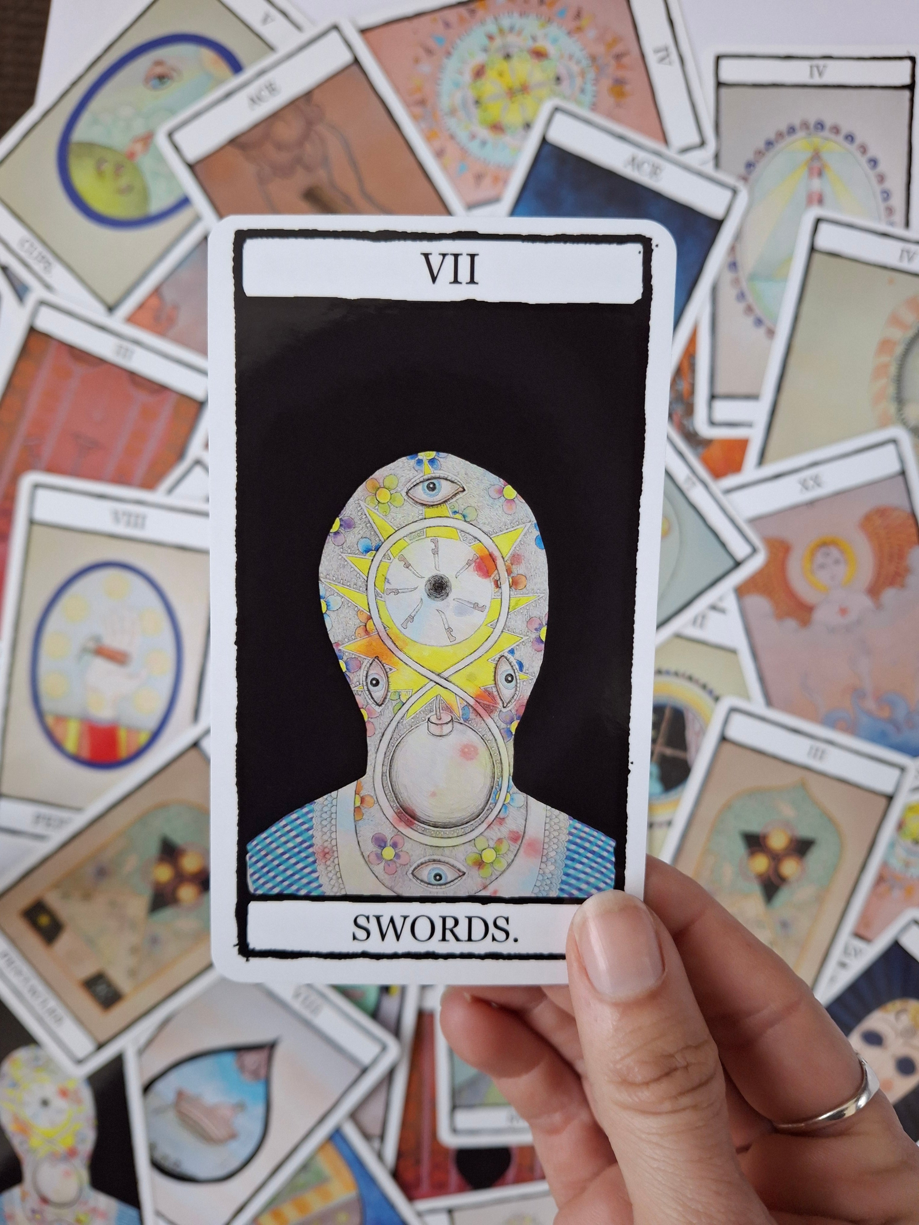 Dark, hand illustrated tarot deck with a surreal illustration of a face with brightly coloured eyes