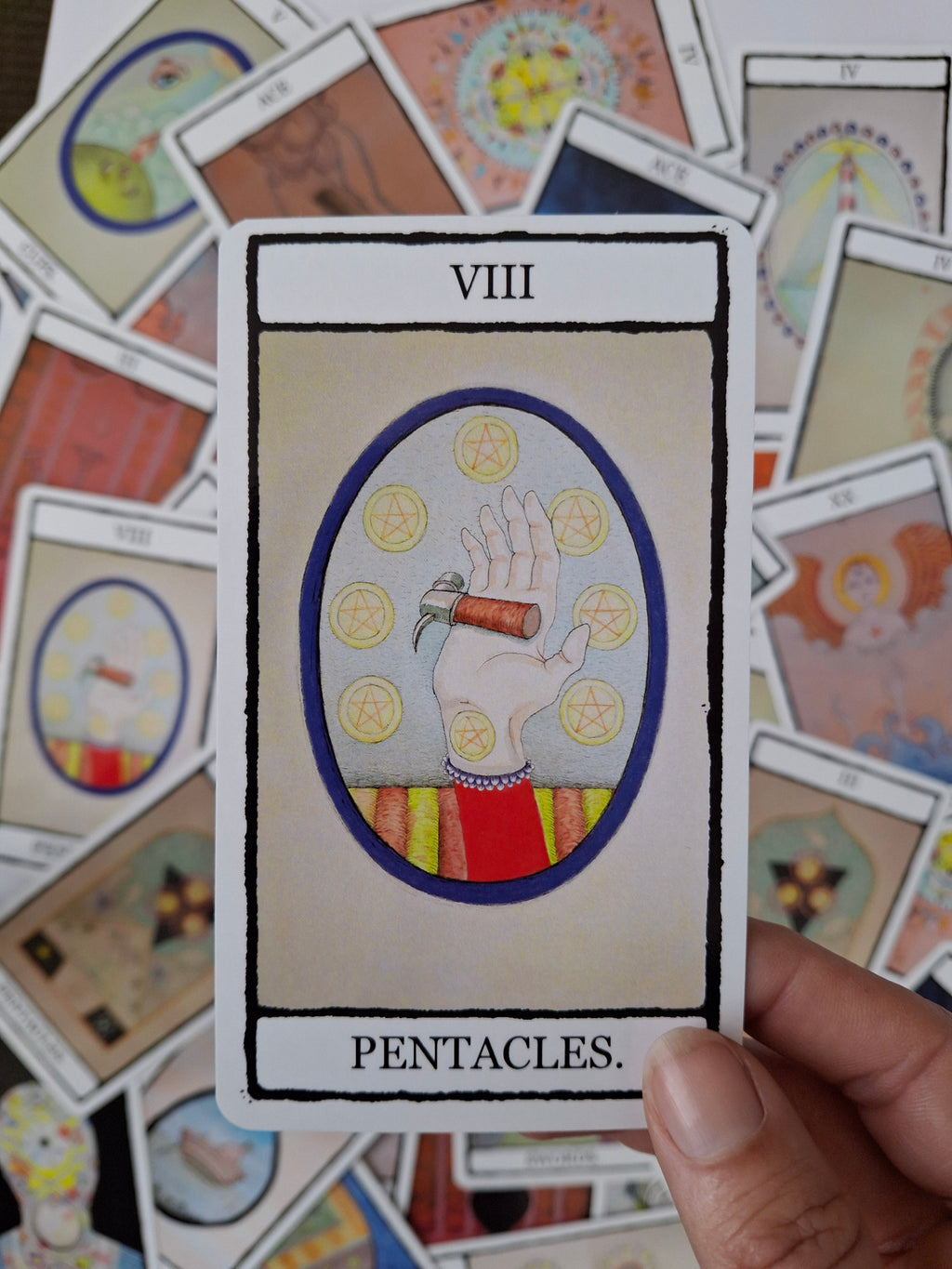 8 of Pentacles tarot card featuring a colourful hand illustrated hand with a cute hammer and 8 pentacles