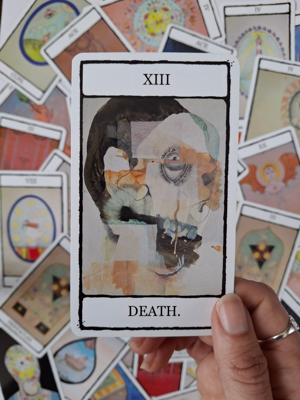 Death card from tarot deck featuring a surreal face with the colours black, white and orange