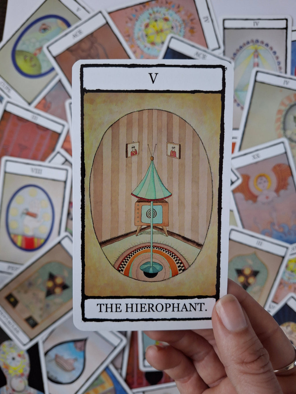 Card from tarot deck hand illustrated with a surreal room with a TV, striped walls and blue lamp
