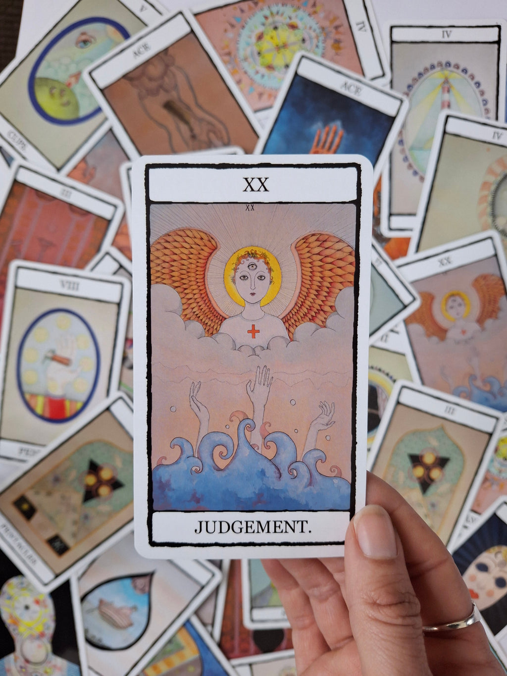 Judgement tarot card with winged figure above mysterious hands coming from the ocean