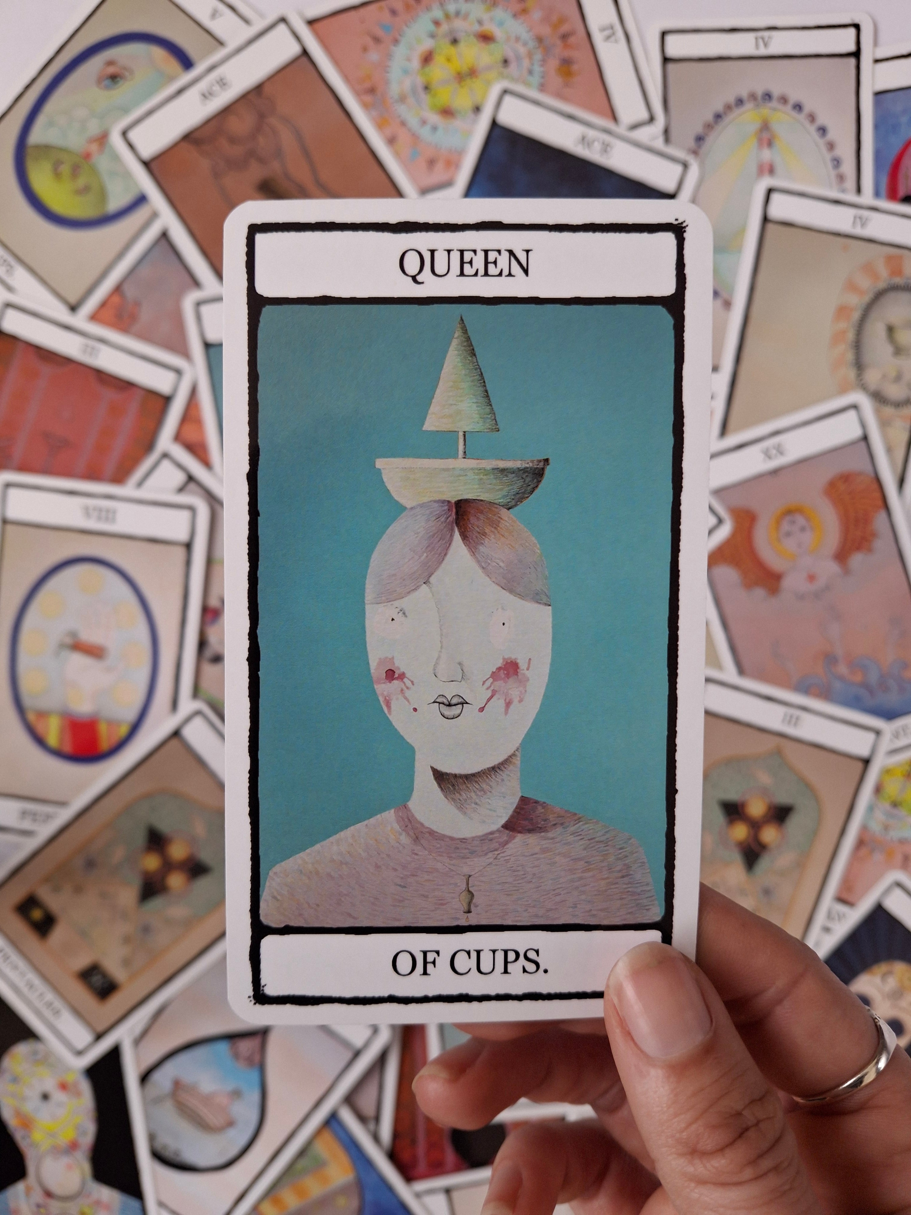 Queen of Cups tarot card featuring original illustration of a woman with a green boat on her head